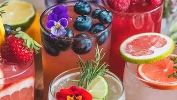 Colorful drinks with fruits and herbs garnish.