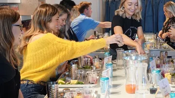 Group of people making cocktails at a bar.