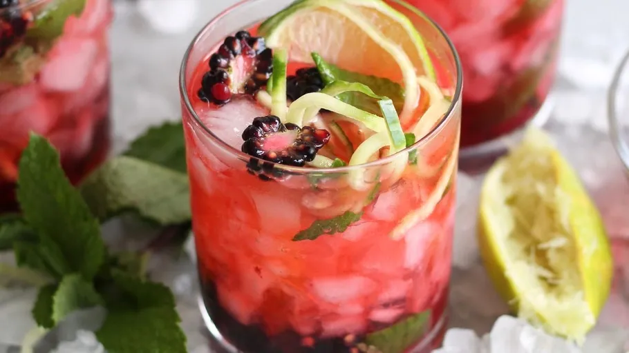 Colorful cocktail with berries and lime slices.