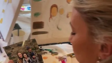 Woman painting family photo on canvas indoors.