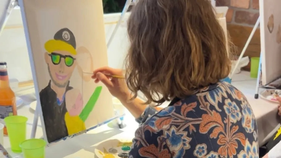 Person painting a colorful portrait indoors.