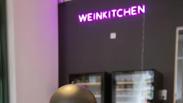 Neon-Schild "Weinkitchen" über Küchengeräten.