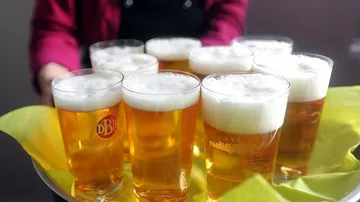Glasses of beer on tray with server.