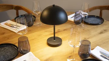 Black lamp on wooden dining table with dishes.