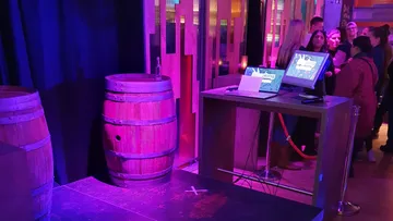 Barrels and computer stand in colorful room.
