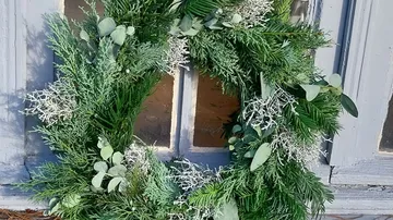 Green wreath hanging on rustic wooden door.