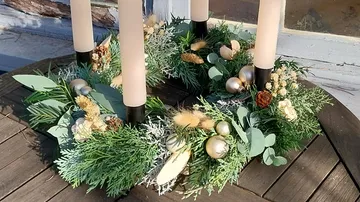 Decorative wreath with candles on wooden table.
