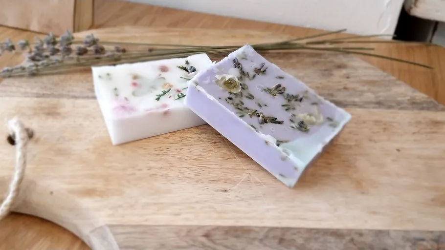 Two floral soaps on wooden board.
