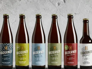Sechs Bierflaschen stehen auf einem grauen Hintergrund.