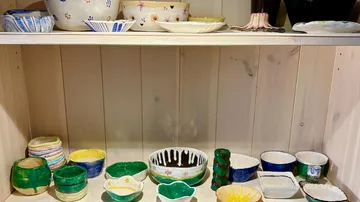 Colorful, handcrafted pottery bowls on wooden shelves.