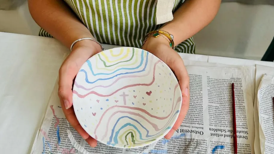 Person holds painted bowl over newspaper.