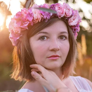 Woman wearing flower crown, outdoors at sunset.