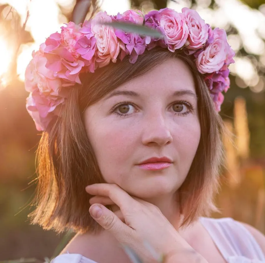 Woman wearing flower crown, outdoors at sunset.