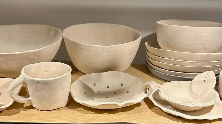 Clay dishes, bowls, and mug on shelf.