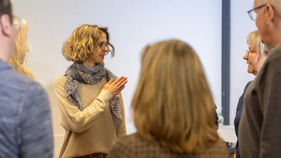 Woman talking to group in room.