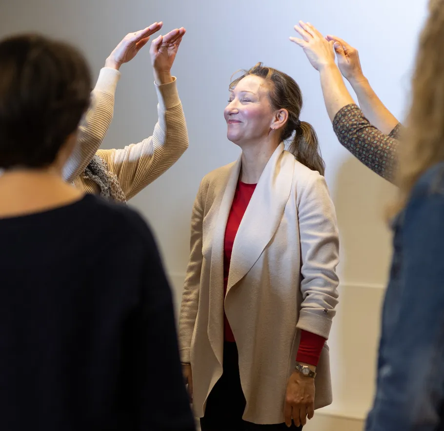 Woman smiling surrounded by raised hands.