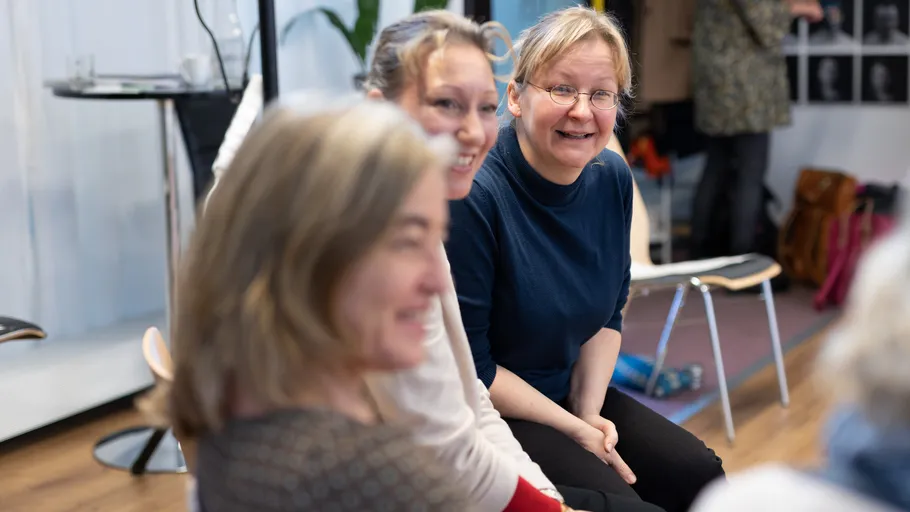 Three women smiling, seated indoors.