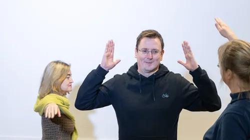 Three people raising arms in a room.