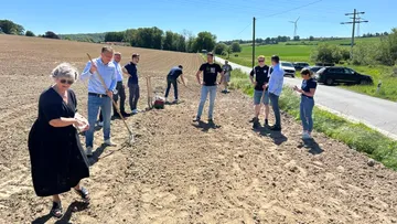 People working in a field near a road.