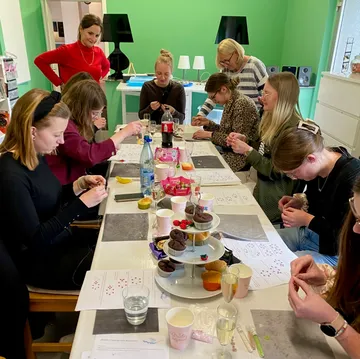 People crafting at table with cupcakes.
