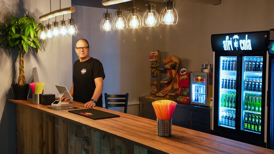 Man behind wooden counter in snack bar.