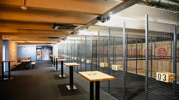 Axe throwing lanes with targets and tables indoors.