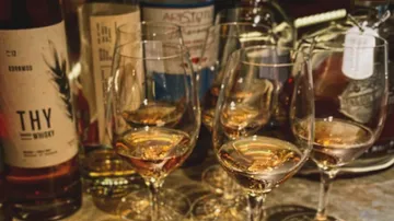 Glasses of whiskey on a cluttered table.