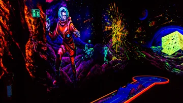 Glowing mini-golf course with neon space theme.