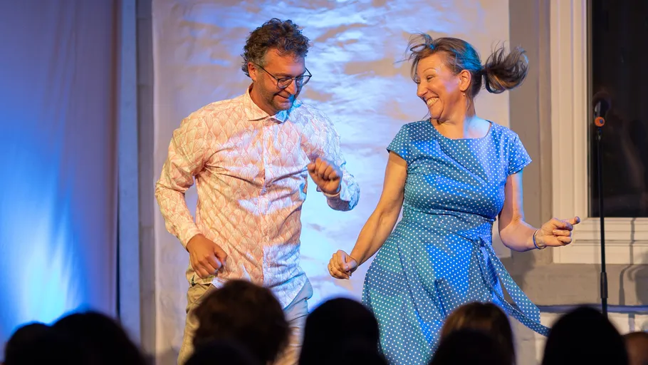 Man and woman happily dancing on stage.