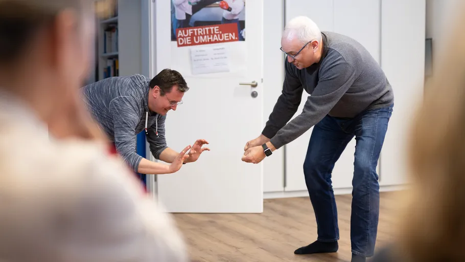 Two men leaning forward in office setting.