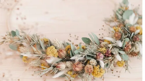 Dried flower wreath on light wood background.