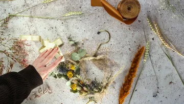 Hand crafting wreath with dried flowers.