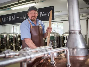 Brewery worker stirs in a large boiler, beer is brewed.
