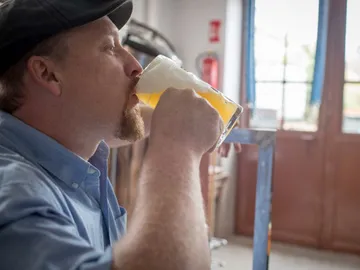 Mann trinkt Bier in einem hellen, gemütlichen Raum.