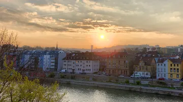 Sonnenuntergang über Stadtbild mit Fluss im Vordergrund.