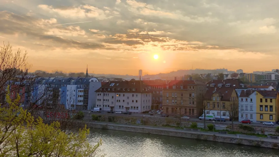 Sonnenuntergang über Stadtbild mit Fluss im Vordergrund.