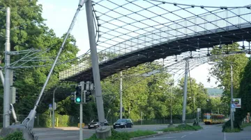 Modern pedestrian bridge over street with cars.