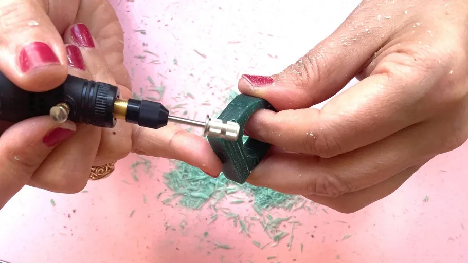 Hands using drill on green wax piece.