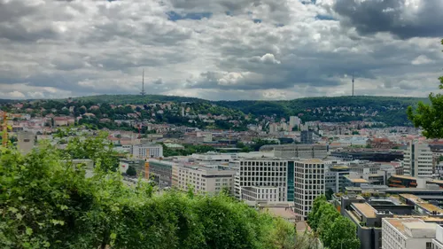 Stadtblick mit Hügeln und wolkigem Himmel.