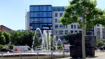 Buildings with fountains and greenery in city.