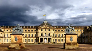 Palace with statues and cloudy sky.