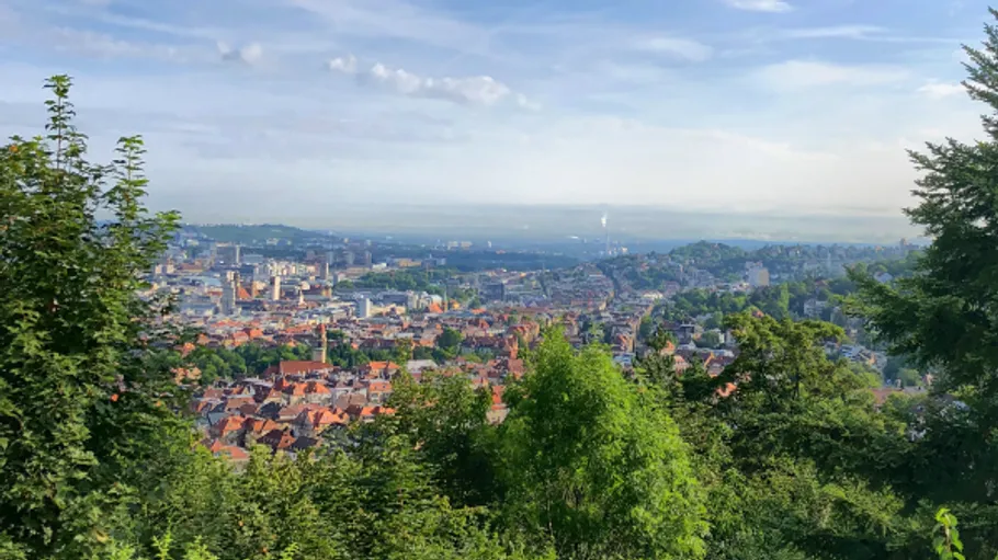 Stadtblick von Hügel mit grünen Bäumen.