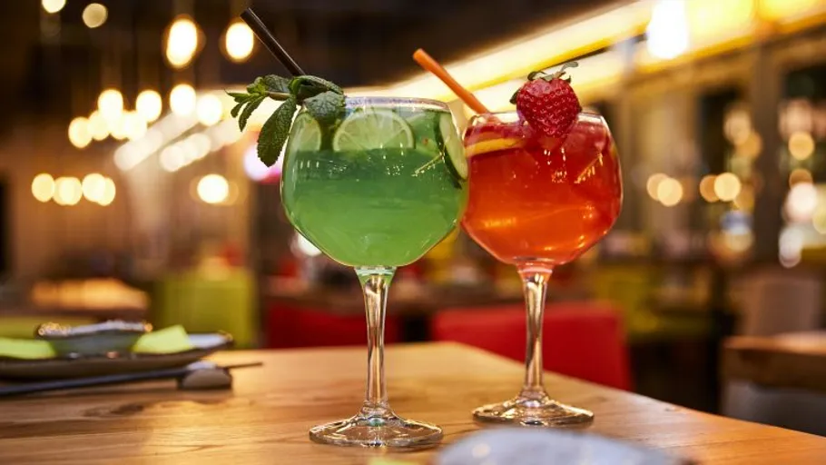 Colorful cocktails on wooden table in bar.