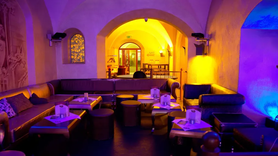 Cozy lounge with colorful lighting, tables, and seating.