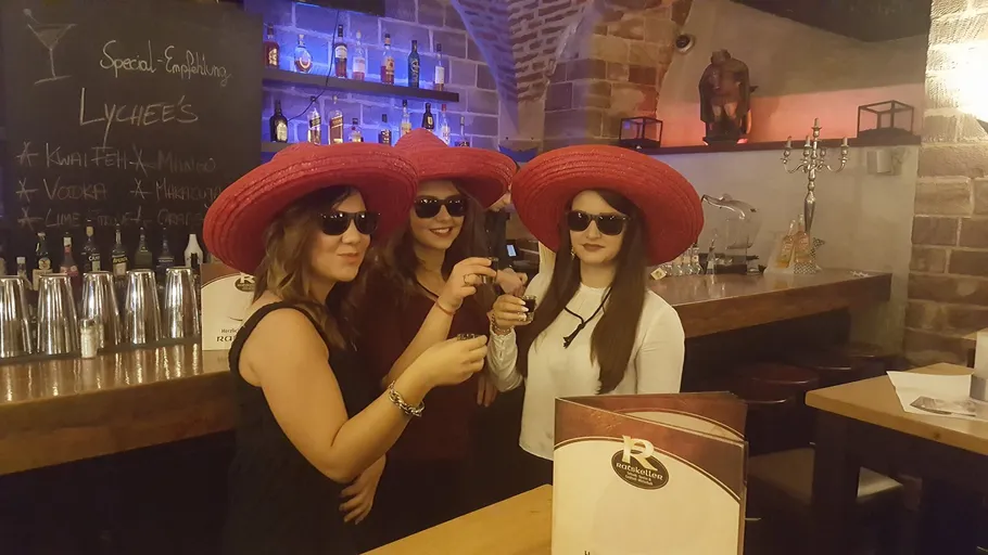 Three women wearing red hats and sunglasses, indoors.