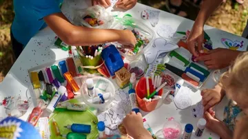 Children crafting at a table outdoors.