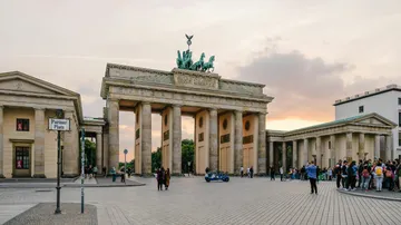 Brandenburg Gate with tourists at sunset.