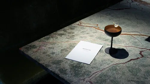 Cocktail and menu on marble table.