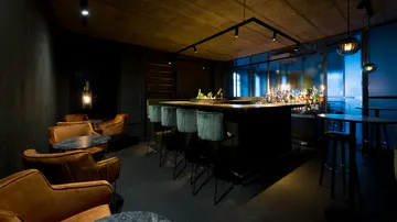 Modern minimalist bar with seating and lighting.