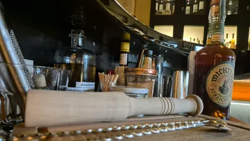 Bar tools and whisky bottle on counter.